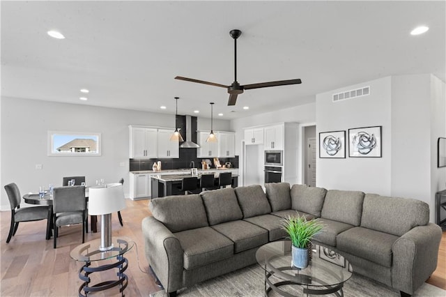 living room with ceiling fan, sink, and light hardwood / wood-style floors