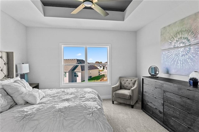 carpeted bedroom with ceiling fan and a raised ceiling