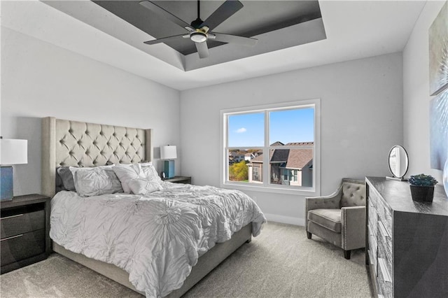 carpeted bedroom featuring ceiling fan and a raised ceiling