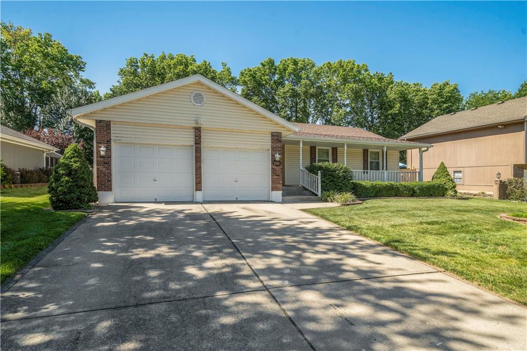 ranch-style home with a garage, a front lawn, and covered porch