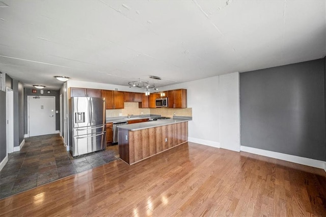 kitchen with sink, a center island, appliances with stainless steel finishes, dark hardwood / wood-style flooring, and decorative backsplash