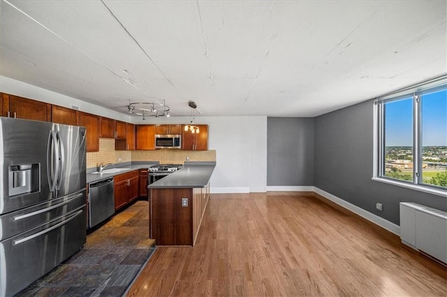 kitchen featuring rail lighting, sink, decorative light fixtures, appliances with stainless steel finishes, and radiator