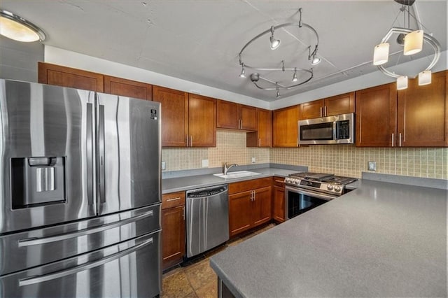 kitchen featuring sink, appliances with stainless steel finishes, hanging light fixtures, tasteful backsplash, and dark tile patterned flooring