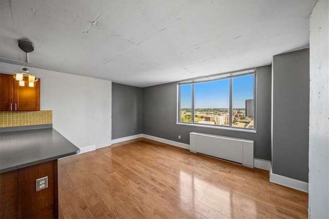 unfurnished living room with radiator heating unit and light hardwood / wood-style floors