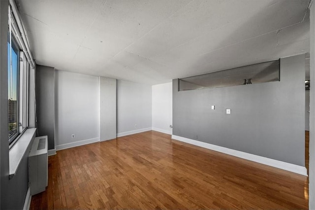 spare room featuring radiator and wood-type flooring