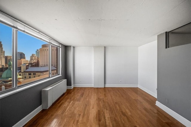 unfurnished room featuring hardwood / wood-style floors and radiator heating unit