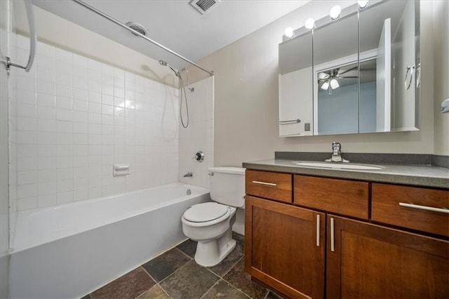 full bathroom featuring vanity, tiled shower / bath, and toilet