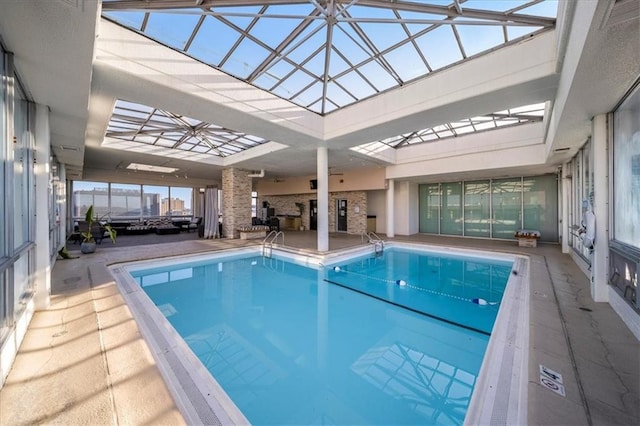 view of pool with glass enclosure and a patio area