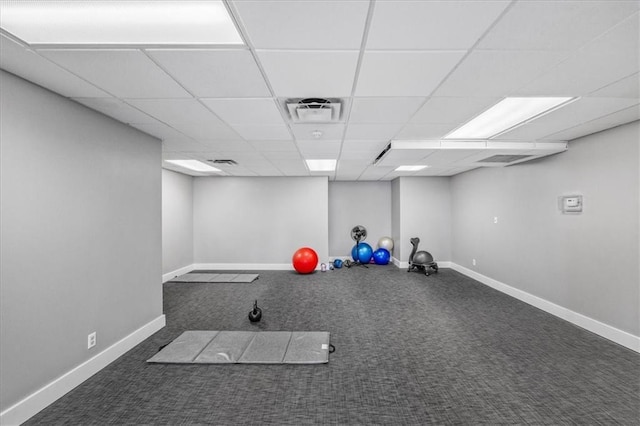 exercise area featuring dark colored carpet and a drop ceiling