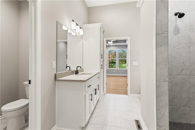 bathroom featuring vanity, ceiling fan, toilet, and tiled shower