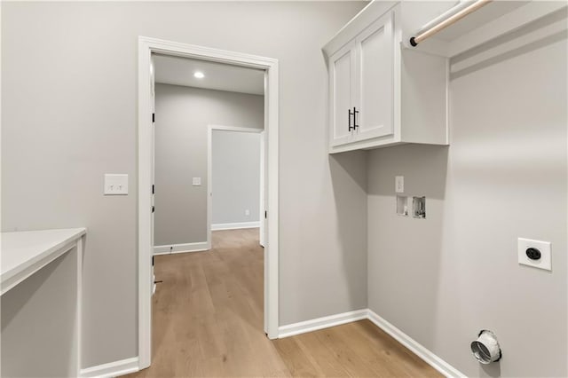 washroom featuring hookup for an electric dryer, hookup for a washing machine, light hardwood / wood-style flooring, and cabinets