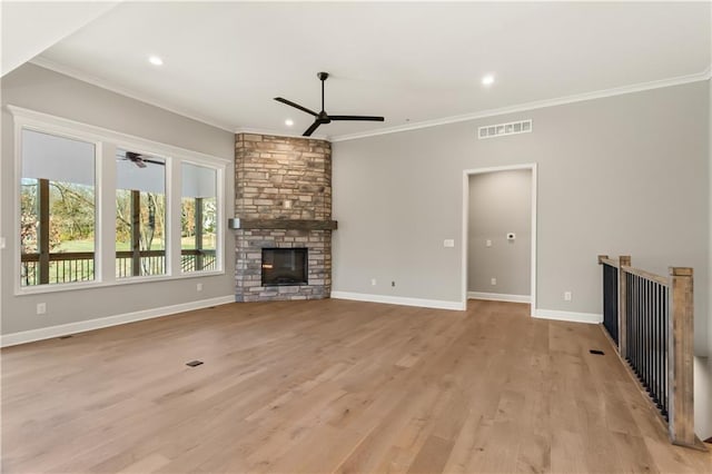 unfurnished living room with a stone fireplace, ornamental molding, and light wood-type flooring