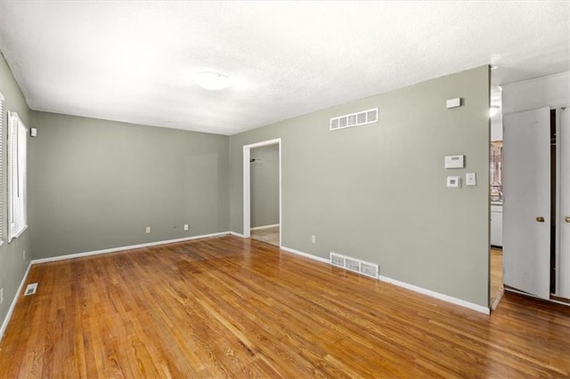 empty room with hardwood / wood-style floors and a textured ceiling