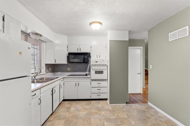 kitchen with white cabinetry, sink, black appliances, and a textured ceiling