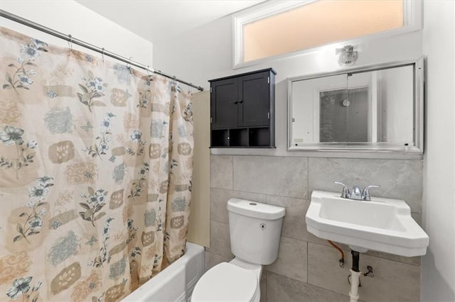 full bathroom with sink, shower / bath combination with curtain, toilet, and tile walls