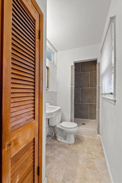 bathroom featuring tiled shower, plenty of natural light, and toilet