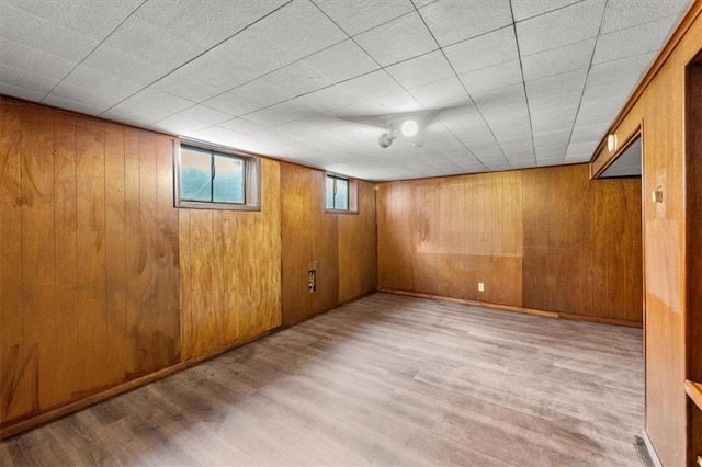 basement with wooden walls and light hardwood / wood-style flooring