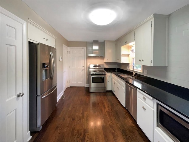 kitchen featuring wall chimney range hood, white cabinets, sink, and stainless steel appliances