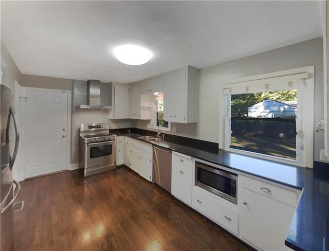 kitchen featuring a wealth of natural light, wall chimney range hood, appliances with stainless steel finishes, and dark hardwood / wood-style floors