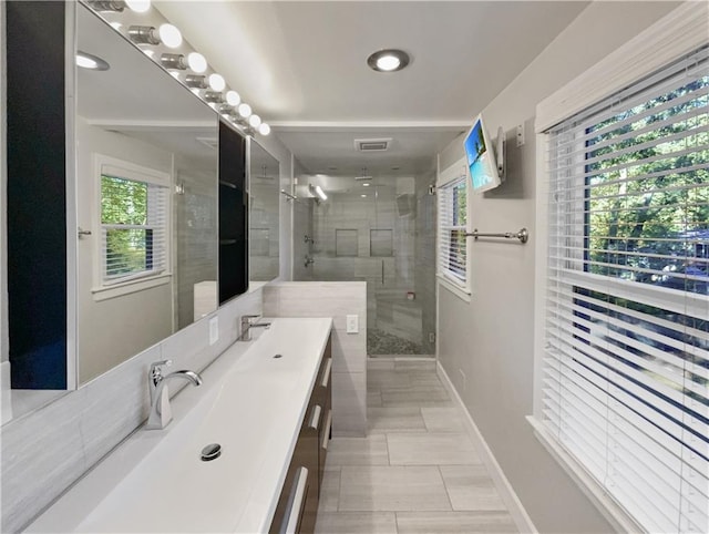 bathroom featuring a shower with door, vanity, and a healthy amount of sunlight