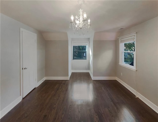 unfurnished room with dark hardwood / wood-style flooring, lofted ceiling, and an inviting chandelier