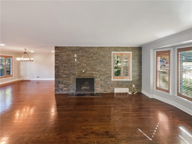 unfurnished living room featuring a stone fireplace, dark hardwood / wood-style flooring, a chandelier, and crown molding