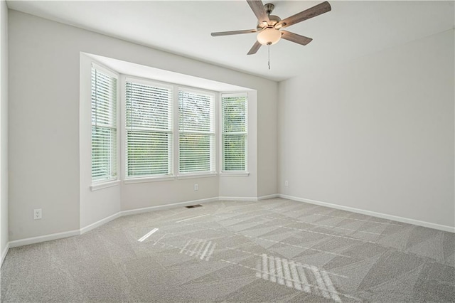 spare room with ceiling fan and light colored carpet