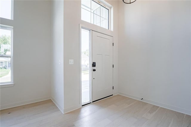 entryway with light wood-type flooring and a towering ceiling