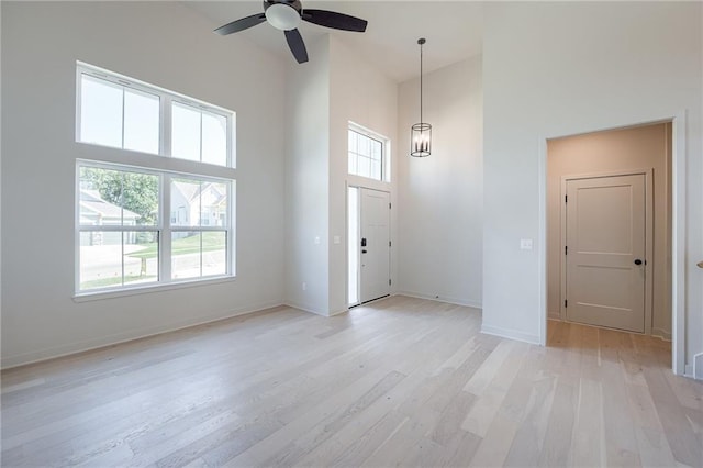 foyer entrance with light hardwood / wood-style flooring, ceiling fan, and a towering ceiling