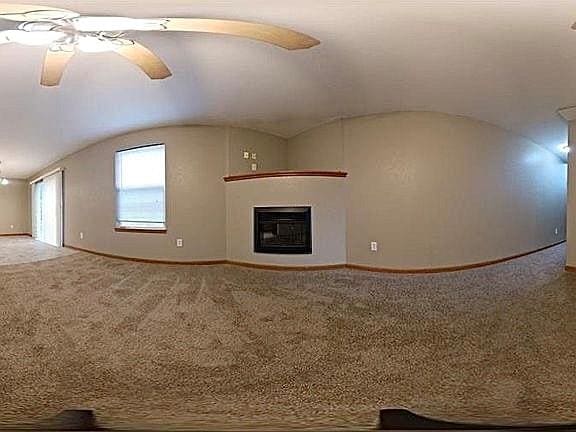 unfurnished living room featuring carpet floors, ceiling fan, and vaulted ceiling