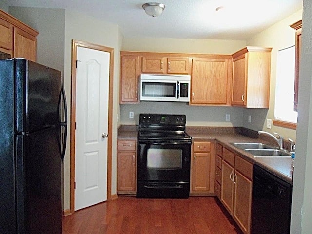 kitchen with dark wood-type flooring, sink, and black appliances