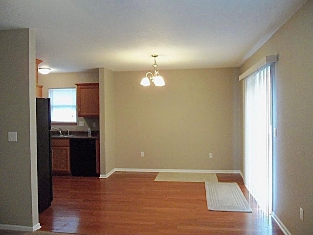 kitchen featuring decorative light fixtures, an inviting chandelier, dark hardwood / wood-style floors, black appliances, and sink