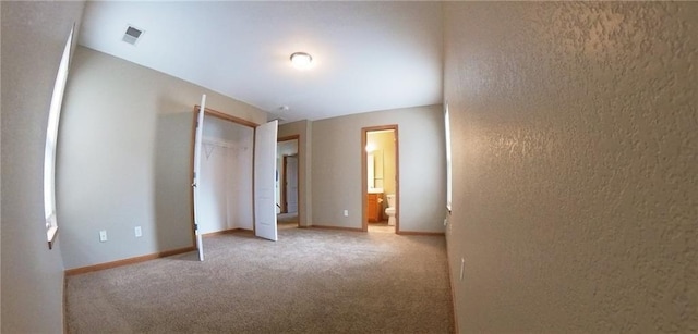 unfurnished bedroom featuring a closet, carpet, connected bathroom, and vaulted ceiling