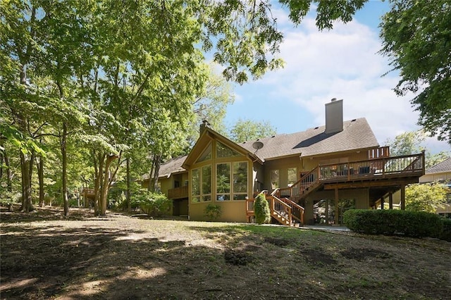 rear view of house featuring a wooden deck and a sunroom