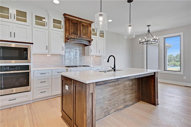 kitchen featuring oven, gas stovetop, a sink, built in microwave, and light wood finished floors