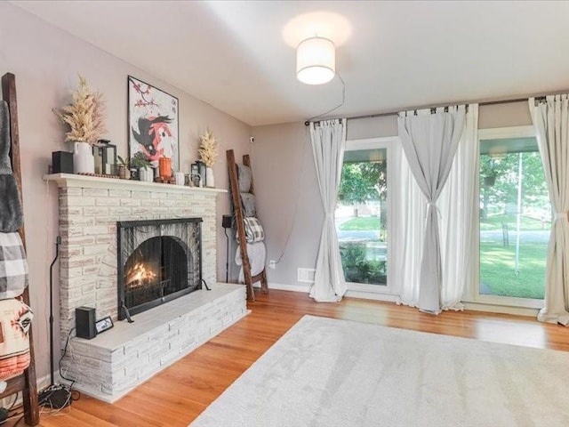 living room featuring hardwood / wood-style floors, plenty of natural light, and a brick fireplace