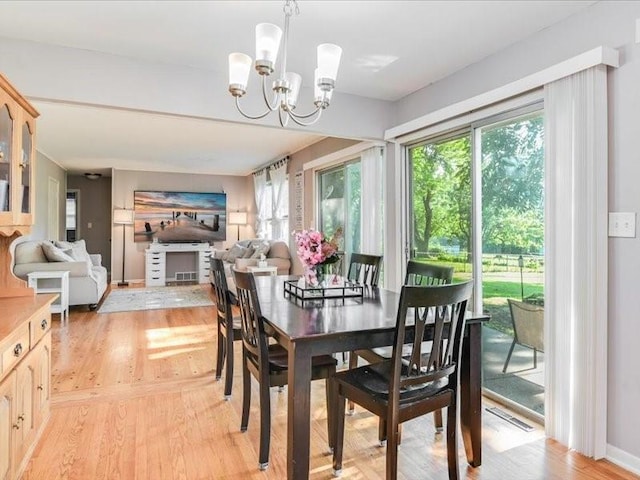 dining area with light wood-type flooring, a chandelier, and a healthy amount of sunlight