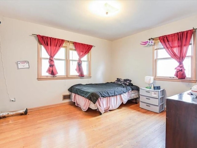 bedroom with light hardwood / wood-style floors and multiple windows