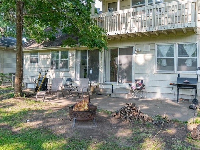 rear view of property featuring a patio, a balcony, and a fire pit