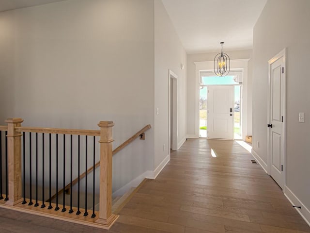 corridor with dark wood-type flooring and an inviting chandelier