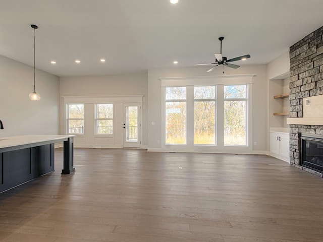 unfurnished living room with ceiling fan, a fireplace, built in features, and dark hardwood / wood-style floors