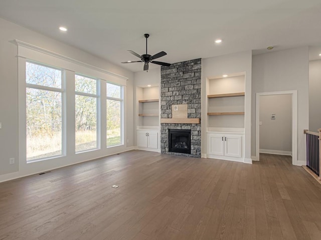 unfurnished living room with ceiling fan, a fireplace, hardwood / wood-style floors, and built in shelves