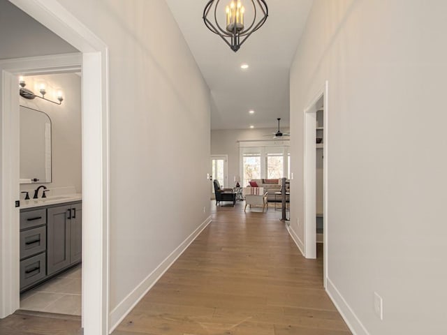 12435 Appaloosa St, Platte City, MO 64079 - corridor with recessed lighting, light wood-style floors, baseboards, a chandelier, and a sink