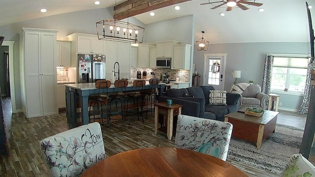 living area with dark wood-type flooring, ceiling fan, beam ceiling, recessed lighting, and high vaulted ceiling