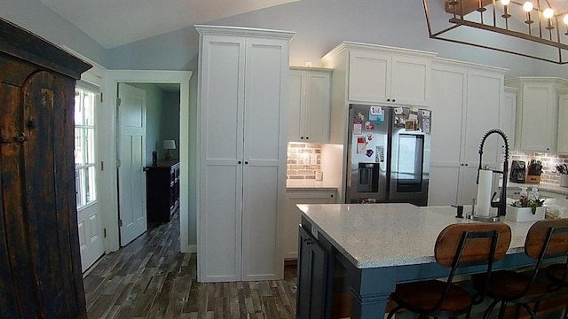 kitchen featuring dark wood-type flooring, light countertops, lofted ceiling, white cabinets, and stainless steel fridge