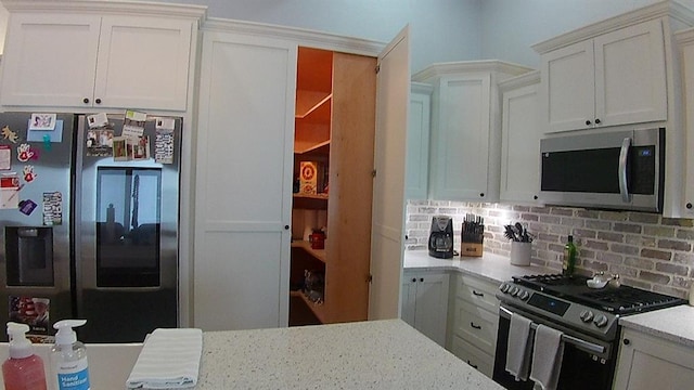 kitchen with backsplash, appliances with stainless steel finishes, and white cabinetry