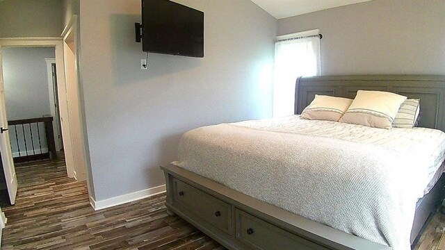 bedroom with dark wood-type flooring and baseboards