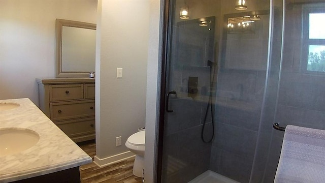 bathroom with toilet, wood finished floors, a shower stall, baseboards, and vanity