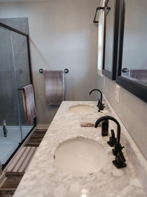 full bath featuring double vanity, a stall shower, and a sink