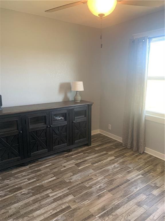 empty room featuring wood finished floors, baseboards, and ceiling fan